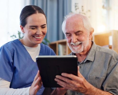 Caregiver Looking At Computer Tablet With Patient