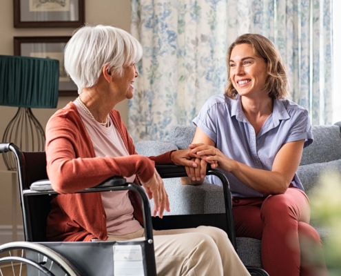Person In Wheelchair Talking With Younger Adult On Couch
